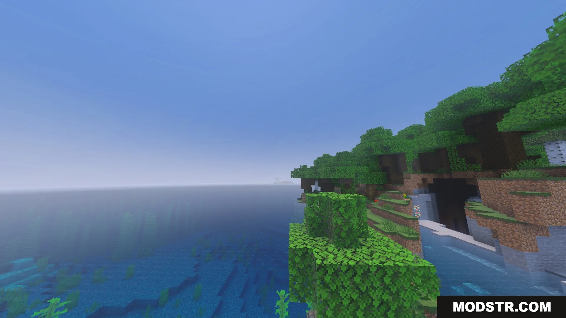 Better Waving Leaves Shader Screenshot 2 Lush green forest biome next to a vast blue ocean in Minecraft