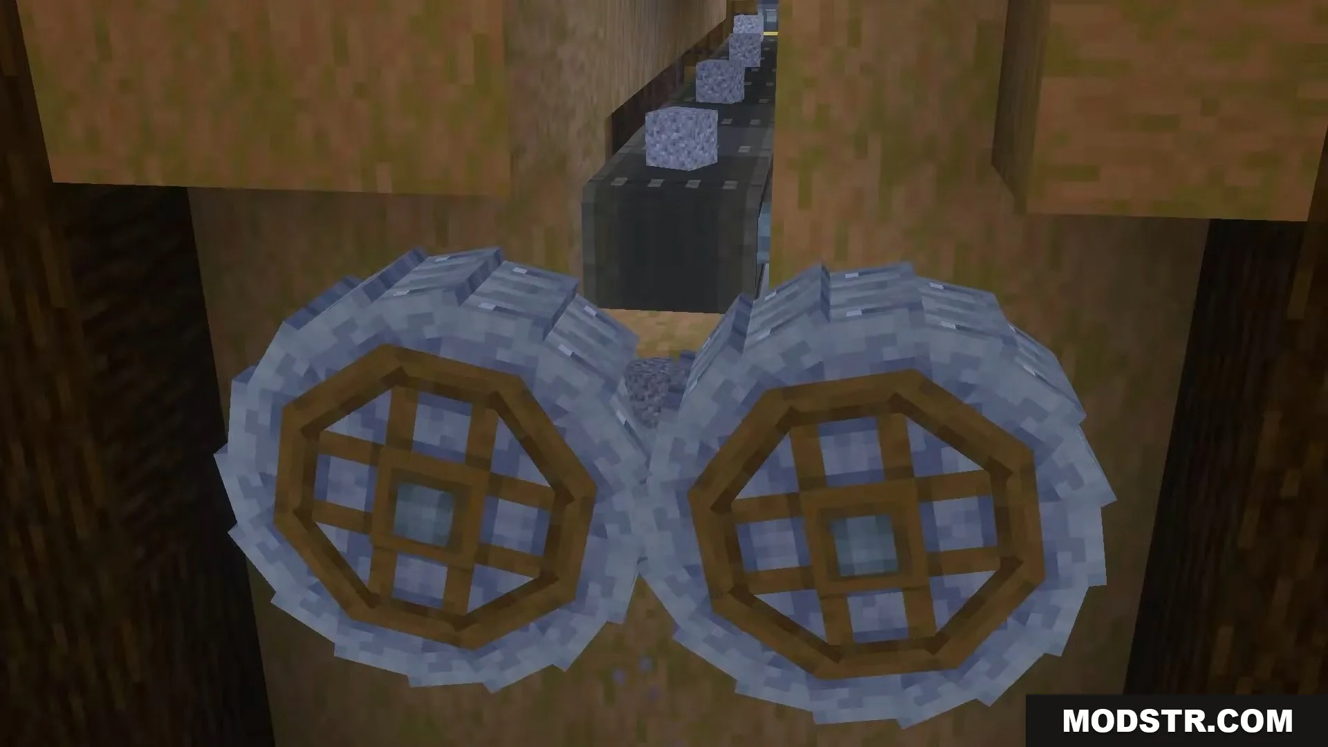 Two large crushing wheels processing cobblestone dropped from a mechanical belt above