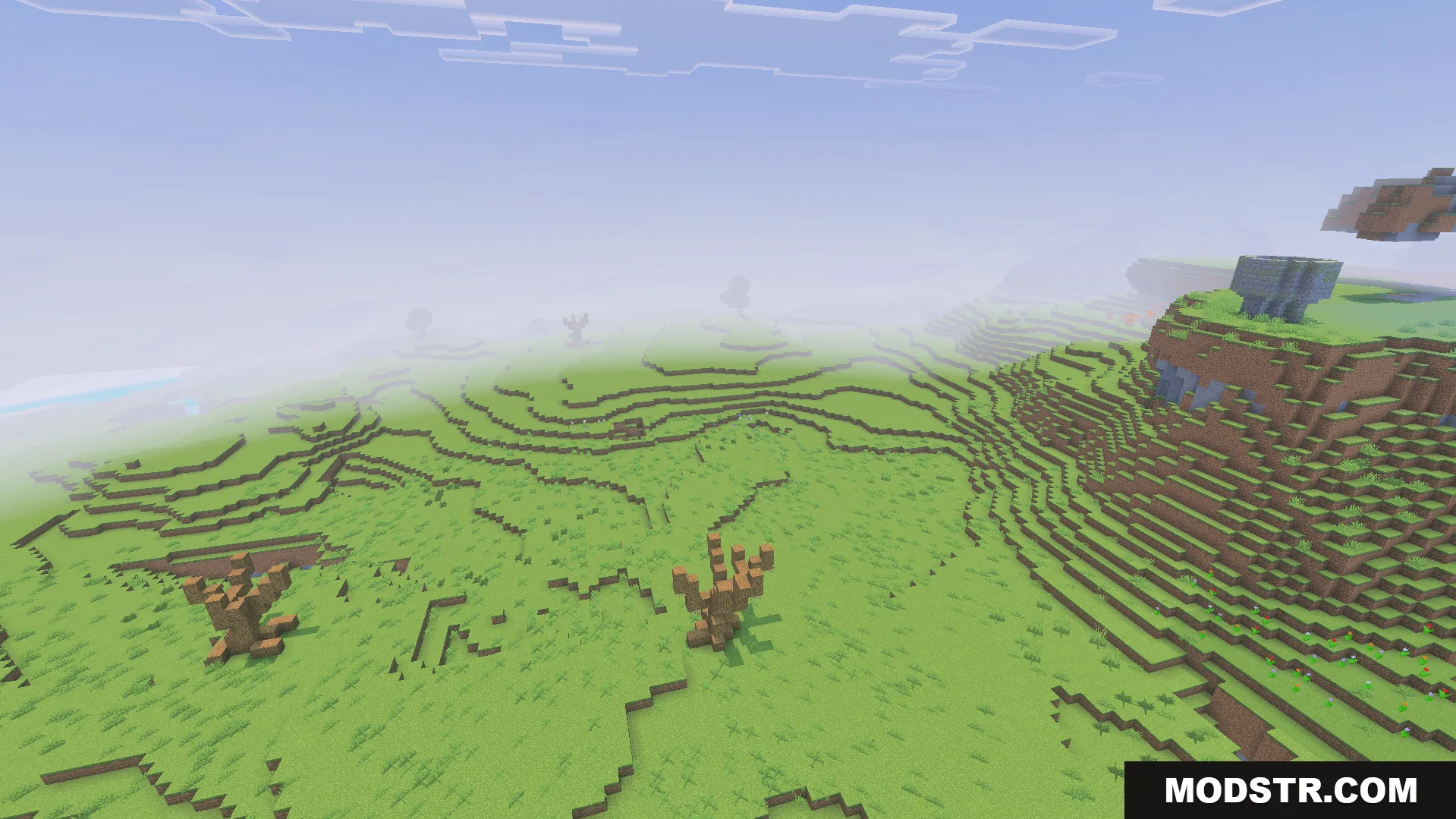 A foggy green landscape featuring custom dead trees and a stone structure