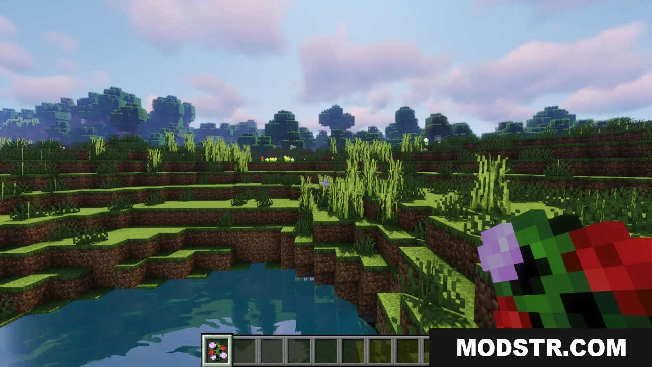 Player holding a colorful floral creeper item in a grassy landscape near water