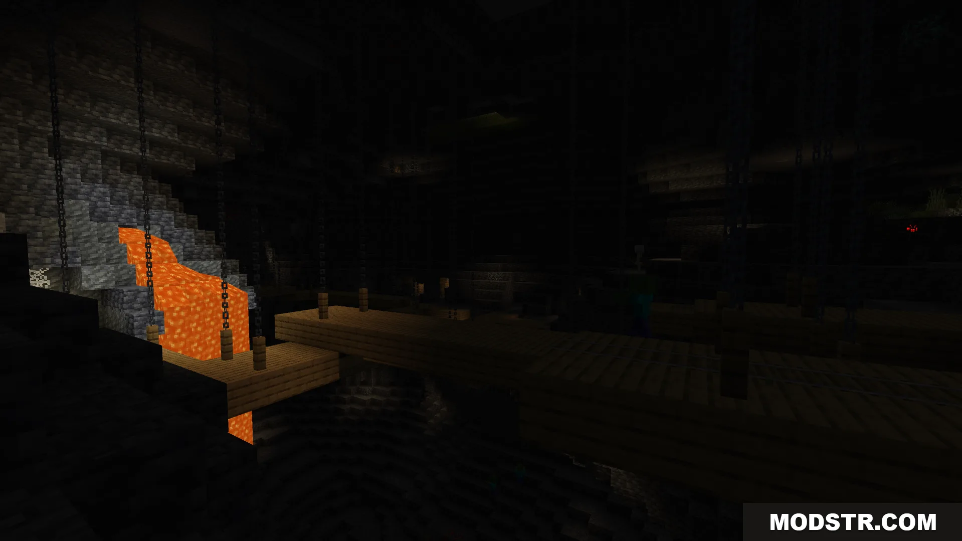 Dark underground cave featuring a lava fall and wooden bridge over water