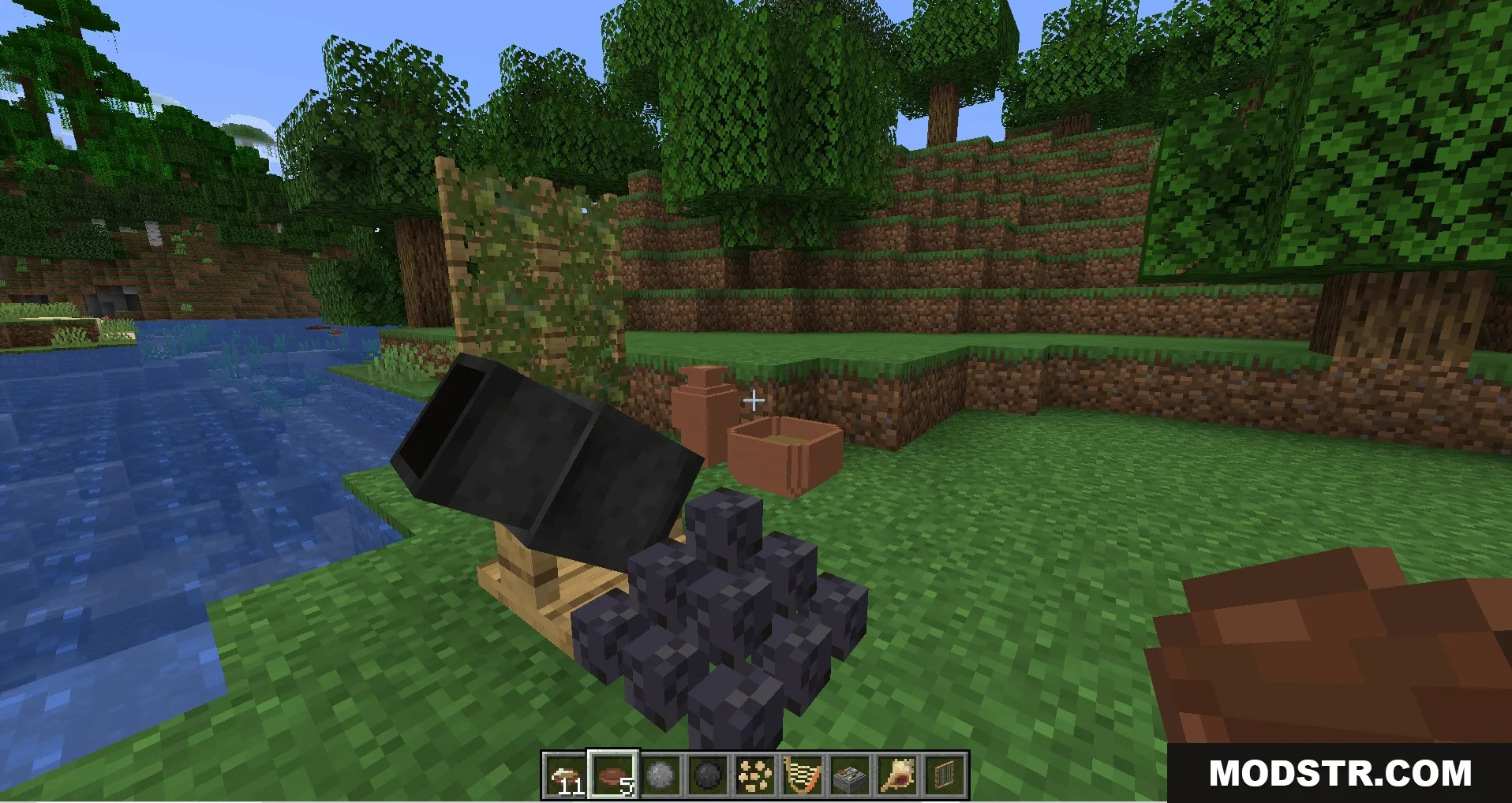 A black cannon and a pile of cannonballs placed on the grass