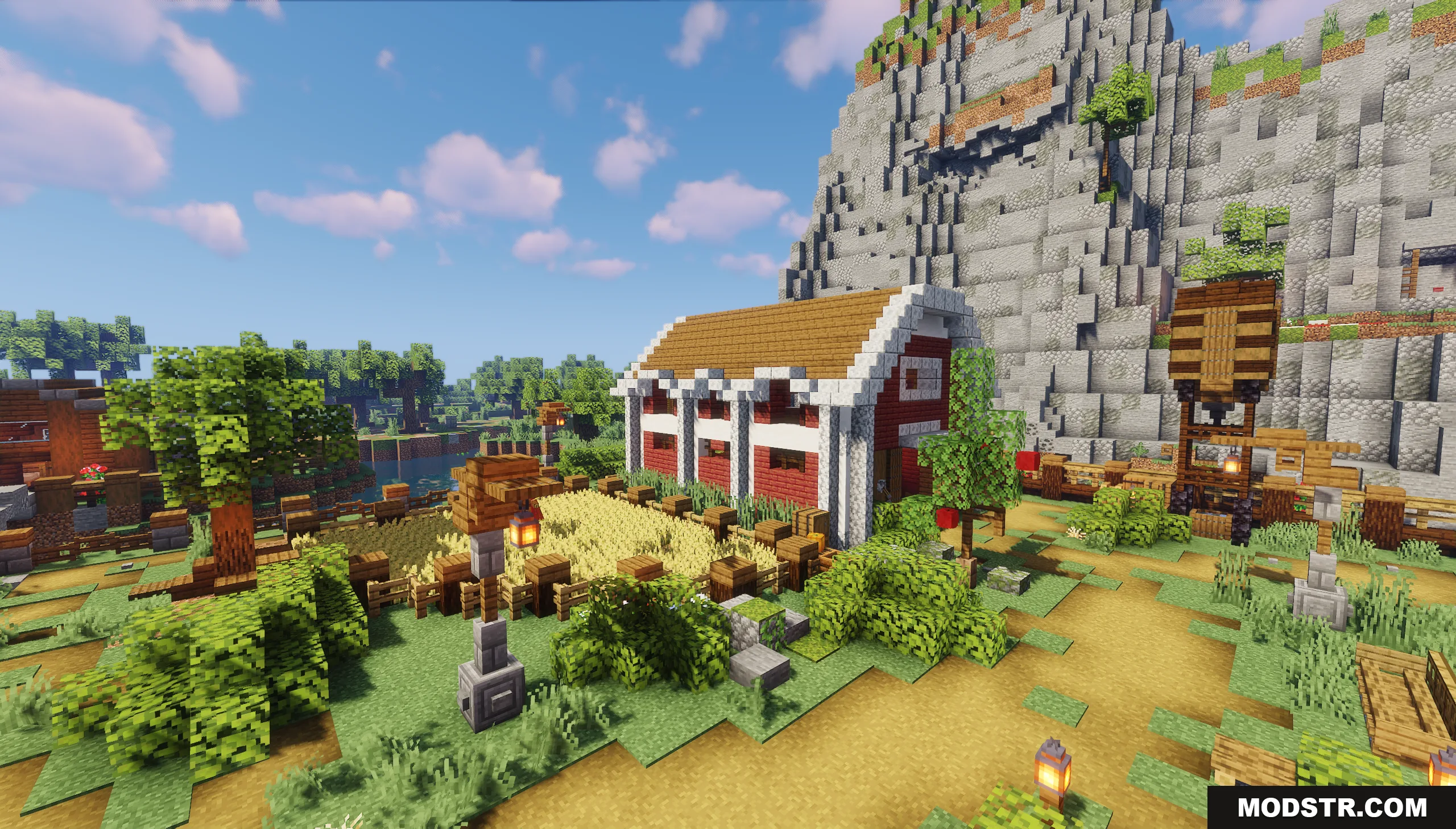 A red barn with white trim stands next to a golden wheat farm