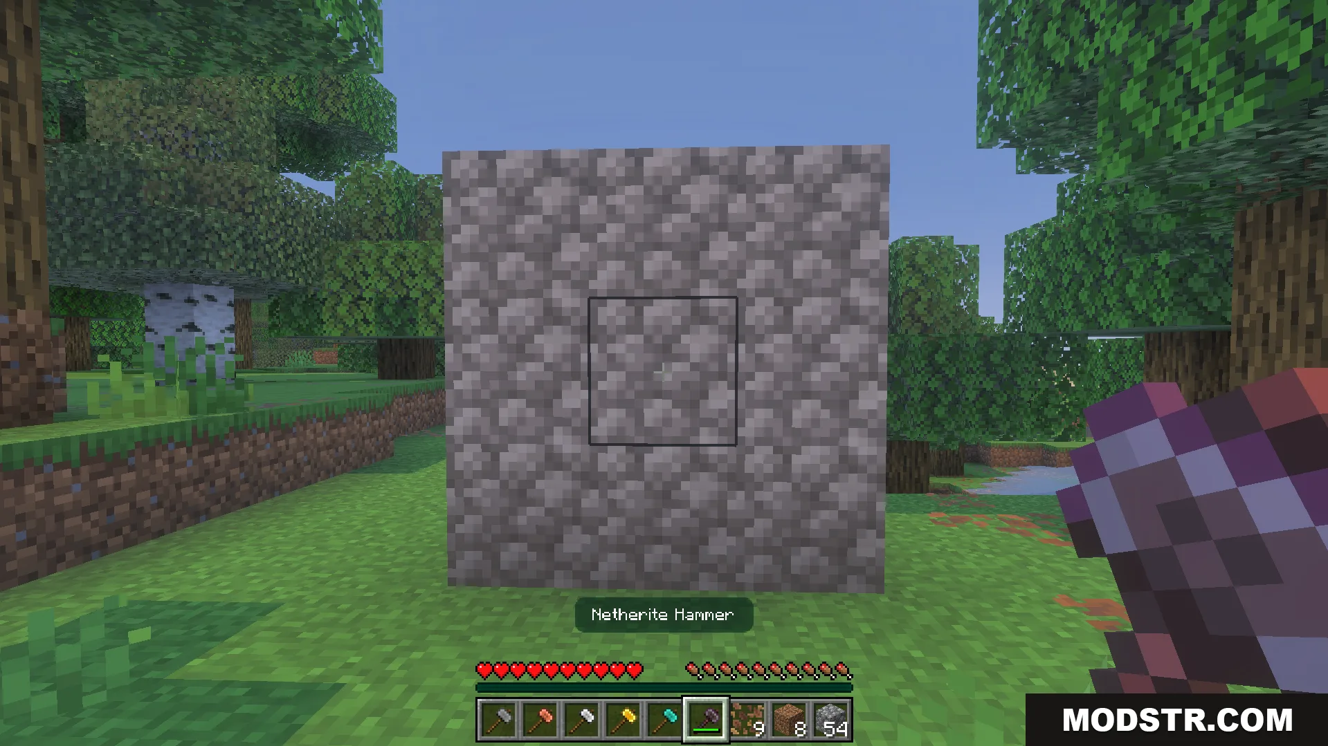 Player holding a netherite hammer facing a three by three wall of cobblestone