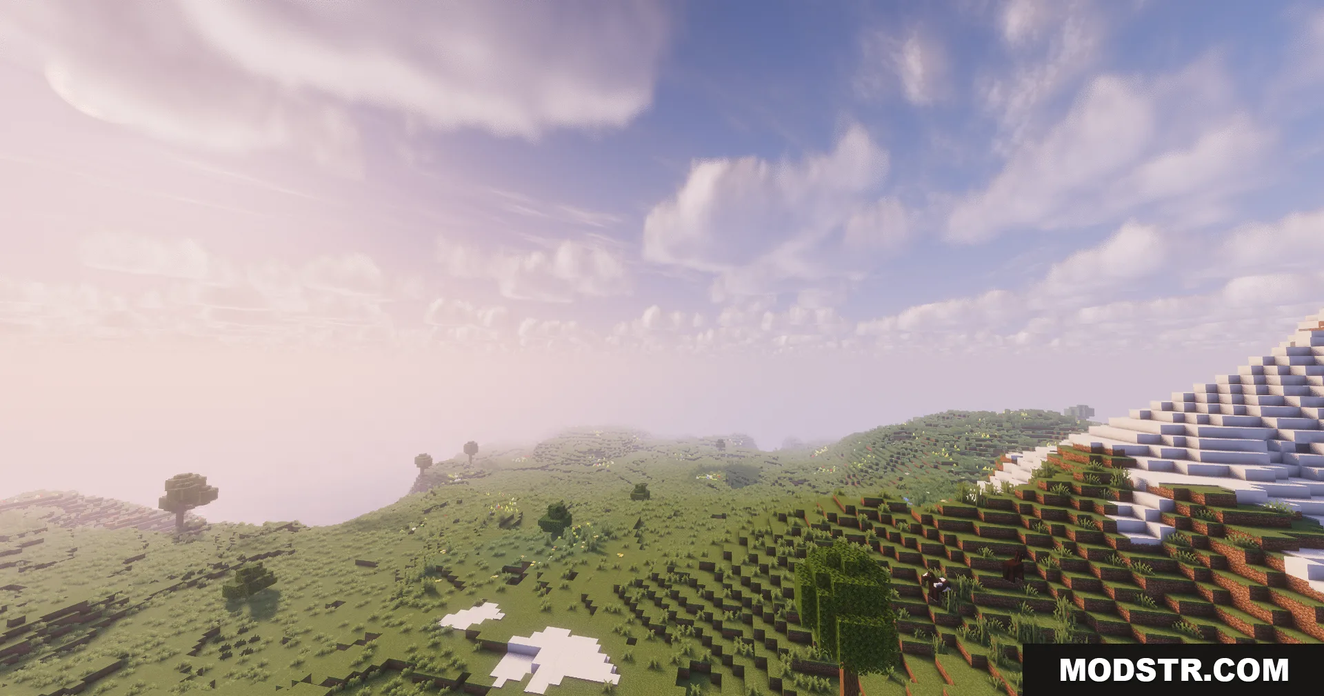 Soft sunlight illuminates a rolling grassy hill with scattered patches of snow