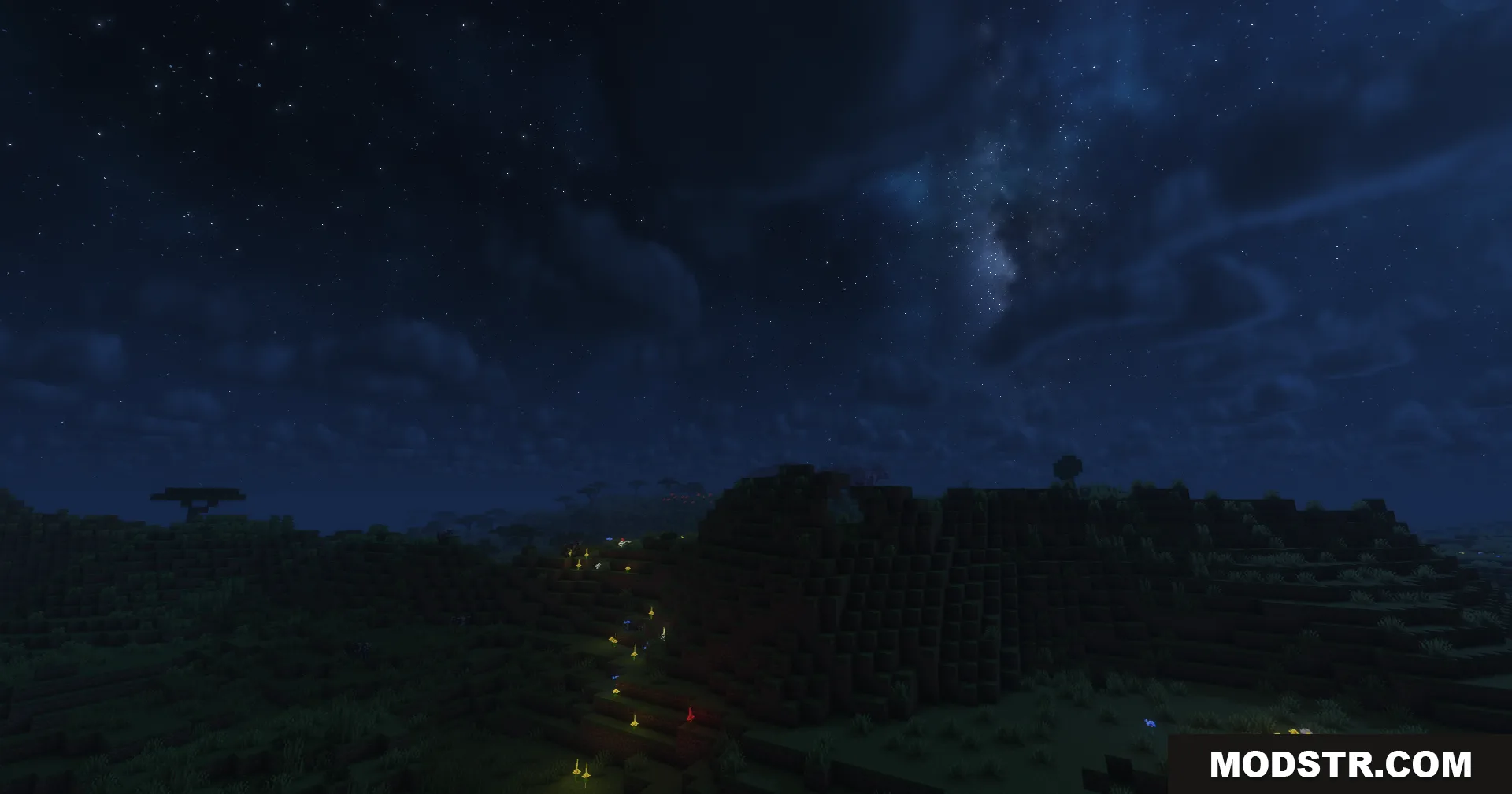 A starry night sky with a galaxy over a dark Minecraft landscape